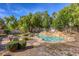 Serene backyard showcasing a pristine pool with rock features, surrounded by manicured landscaping and a cozy patio set at 10528 Meadow Mist Ave, Las Vegas, NV 89135