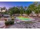 Night view of a private backyard with a captivating pool and rock waterfall, surrounded by lush greenery and a cozy fire pit at 10528 Meadow Mist Ave, Las Vegas, NV 89135