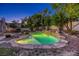 Tranquil backyard showcasing a unique, illuminated pool with rock features, set amidst lush landscaping for serene evenings at 10528 Meadow Mist Ave, Las Vegas, NV 89135