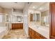 Bright bathroom with double sinks, wood cabinets, a glass shower, and a soaking tub at 10528 Meadow Mist Ave, Las Vegas, NV 89135