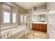 Bright bathroom featuring a soaking tub, glass shower, and wood cabinets with tiled flooring at 10528 Meadow Mist Ave, Las Vegas, NV 89135