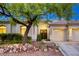 Attractive home front with desert landscaping, double-door entry, and a two-car garage, enhanced by warm exterior lighting at 10528 Meadow Mist Ave, Las Vegas, NV 89135