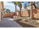 A view of the backyard featuring a concrete patio, brick walls, gravel, and palm trees at 10765 Muscari Way, Las Vegas, NV 89141