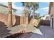 A view of the backyard featuring a concrete patio, brick walls, gravel, and palm trees at 10765 Muscari Way, Las Vegas, NV 89141