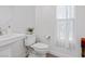 Stylish half bathroom featuring a pedestal sink, a white toilet, and a window with natural light at 108 Kimberlite Dr, Henderson, NV 89011