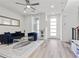 Bright living room with light grey floors, ceiling fan, blue couch, clear coffee table, and white walls at 108 Kimberlite Dr, Henderson, NV 89011