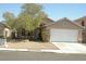 Tan single story home with low maintenance yard and white two car garage door at 108 Zenith Point Ave, North Las Vegas, NV 89032