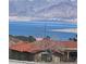 Exterior shot of a house with a terracotta roof, framed by a lake and mountains in the background at 117 Forest Ln, Boulder City, NV 89005