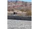 View of a parking area and desert terrain from paver patio, bordered by a cinder block retaining wall at 117 Forest Ln, Boulder City, NV 89005