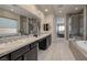 An elegant bathroom featuring double sinks, a glass enclosed shower, and a soaking tub at 12 Hilltop Crest St, Henderson, NV 89011