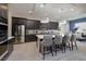 A modern kitchen flows into dining area, featuring an island with seating and stainless steel appliances at 12 Hilltop Crest St, Henderson, NV 89011