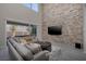 Modern living room featuring a stone accent wall, a plush sectional sofa, and an open view to the backyard at 12 Hilltop Crest St, Henderson, NV 89011