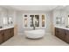 Bright bathroom featuring dual vanities with stone countertops and a modern free-standing tub with views at 1312 Enchanted River Dr, Henderson, NV 89012