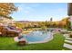 A large backyard pool with a rock slide, lush landscaping, and mountain views at 1312 Enchanted River Dr, Henderson, NV 89012