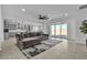 Open-concept living room features a plush couch, modern ceiling fan, and sliding glass doors to the backyard at 136 Mosso Niente Pl, Henderson, NV 89011