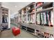 Spacious walk-in closet featuring custom shelving, drawers, shoe racks and a red leather ottoman at 1786 Diamond Rim Ct, Henderson, NV 89012