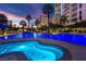 Night view of the pool and hot tub glowing with colorful lights surrounded by palm trees at 322 Karen Ave # 1101, Las Vegas, NV 89109