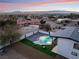 Stunning aerial view of a home with a pool, showcasing beautiful sunset views and mountain backdrop at 6885 Stone Dr, Las Vegas, NV 89110