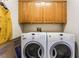 Well-lit laundry room featuring front loading washer and dryer with upper cabinets at 7076 Oakleigh Dr, Las Vegas, NV 89110