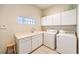 Bright laundry room with a tiled floor, utility sink, white cabinets, a front loading washer, and a dryer at 8875 Steven Chase Ct, Las Vegas, NV 89149