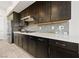 Close-up of kitchen featuring dark cabinets, stainless steel appliances and light countertops with neutral backsplash at 11900 Star Grass Ave, Las Vegas, NV 89138