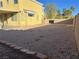 View of the yellow home's backyard with desert landscaping and block wall at 161 Lenape Heights Ave, Las Vegas, NV 89148