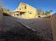 View of the desert landscaped backyard and a yellow home exterior under a blue sky at 161 Lenape Heights Ave, Las Vegas, NV 89148