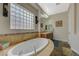 Luxurious bathroom featuring a soaking tub with tile surround and dual sink vanity at 2124 Pont National Dr, Henderson, NV 89044