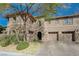 Two-story home with a tandem two-car garage, stone accents, and mature trees for shade at 2124 Pont National Dr, Henderson, NV 89044