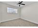 Neutral bedroom features a ceiling fan, window with blinds, and neutral carpet flooring at 3700 San Angelo Ave, Las Vegas, NV 89102