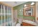 Charming bathroom with a bathtub, shower, and vanity, complemented by green and beige accents at 4424 Shady Hollow Ave, North Las Vegas, NV 89031