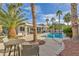 Backyard oasis with a sparkling pool, patio furniture, and lush palm trees at 6005 Blowing Bellows St, Las Vegas, NV 89130