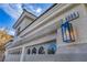 Close-up of a home's exterior features, including a garage and decorative light fixture at 6005 Blowing Bellows St, Las Vegas, NV 89130