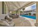 Relaxing covered patio featuring comfortable seating overlooking the sparkling pool and lush landscaping at 6005 Blowing Bellows St, Las Vegas, NV 89130