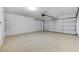 An empty two car garage with a speckeled floor and a standard garage door at 6027 Stone Hollow Ave, Las Vegas, NV 89156