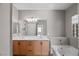 Bathroom featuring double sink vanity, large mirror, soaking tub, and ample natural light at 6151 Moonlight Sonata Ave, Las Vegas, NV 89122