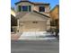 Two-story house with beige exterior, green shutters, and a two-car garage at 6460 Raven Hall St, North Las Vegas, NV 89084