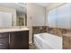 Bright bathroom with a vanity, decorative tile accents and a soaking tub at 7516 Evening Melody Ct, Las Vegas, NV 89178