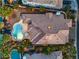 Aerial view of a luxury home with a tile roof and large pool surrounded by palm trees and lush landscaping at 8808 Rozetta Ct, Las Vegas, NV 89134