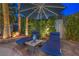 Relaxing outdoor patio area with plush lounge chairs, a shade umbrella, and lush greenery at 8808 Rozetta Ct, Las Vegas, NV 89134