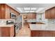 A well-lit kitchen with wood cabinets, stainless steel appliances, granite countertops, and stylish backsplash at 8908 Rocky Shore Dr, Las Vegas, NV 89117