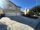 Two-story beige home with a two-car garage, concrete driveway and landscaping at 9543 Antelope Bend Ct, Las Vegas, NV 89148