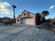 Attached two-car garage with a wide driveway, desert landscaping, and clear blue sky at 9552 Gold Bank Dr, Las Vegas, NV 89134