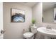 Stylish half bathroom with a pedestal sink, modern fixtures, and decorative wall art at 11832 Dragontail Peak Ave, Las Vegas, NV 89138