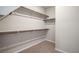 A simple walk-in closet featuring wood shelving and neutral-colored carpet at 11832 Dragontail Peak Ave, Las Vegas, NV 89138