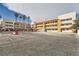 Apartment building with parking lot, featuring balconies, palm trees, and a partially cloudy sky at 1381 E University Ave # 203, Las Vegas, NV 89119