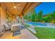 Outdoor living area with a pool and spa, surrounded by trees and a covered dining area at 19 Desert Highlands Dr, Henderson, NV 89052