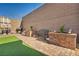 Inviting backyard space with artificial turf, garden, and a brick-paved pathway with a privacy wall at 3491 Argiento Ave, Henderson, NV 89044