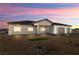 Stunning single-story home featuring a three-car garage and desert landscaping at dusk at 3520 Malibou Ave, Pahrump, NV 89048
