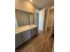 Bathroom with double sinks, gray cabinets, wood-look tile and entry to additional rooms at 7199 Twilight Rider Ct, Las Vegas, NV 89118